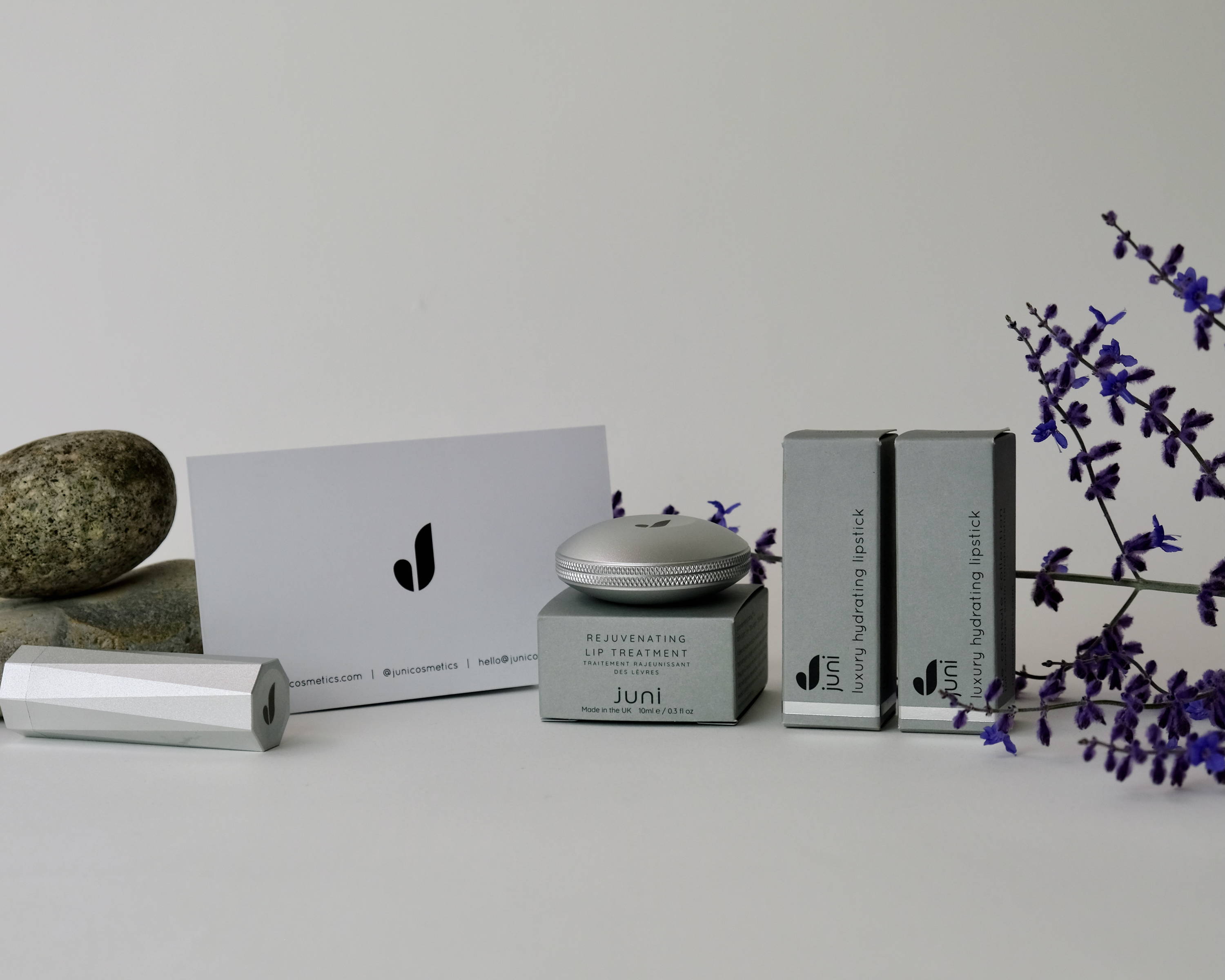 Image of a selection of Juni products displayed with some flowers and decorative rocks