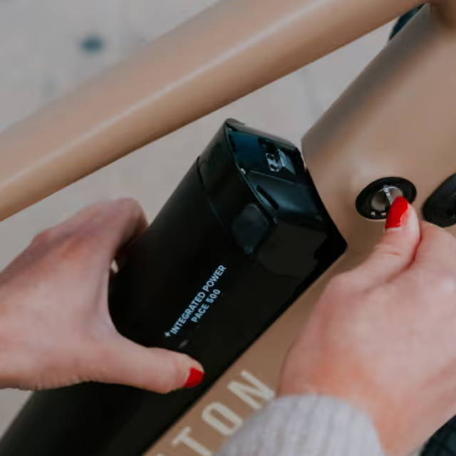 a woman removing a battery from an aventon electric bike