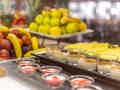 Ein farbenfrohes Buffet mit frischem Obst wie Bananen, Äpfeln und Ananas sowie kleinen Dessertbechern.