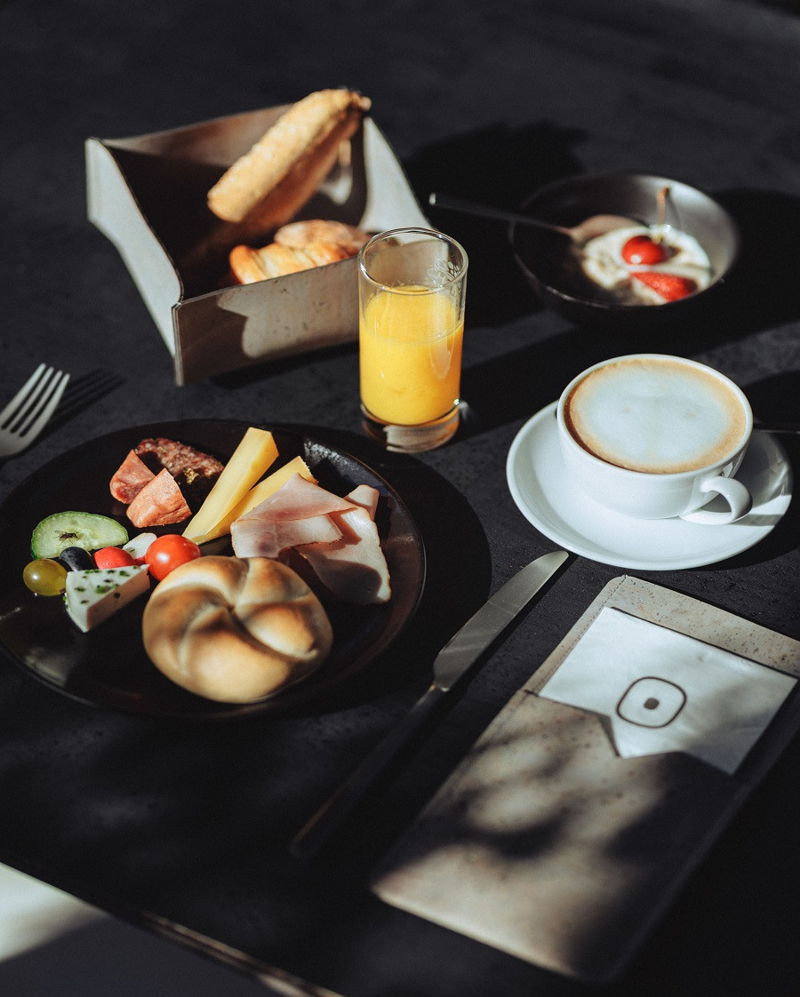 Hotelgast am Frühstückstisch mit Kaffee und Brot im 4-Sterne Hotel in Mellau, Bregenzerwald