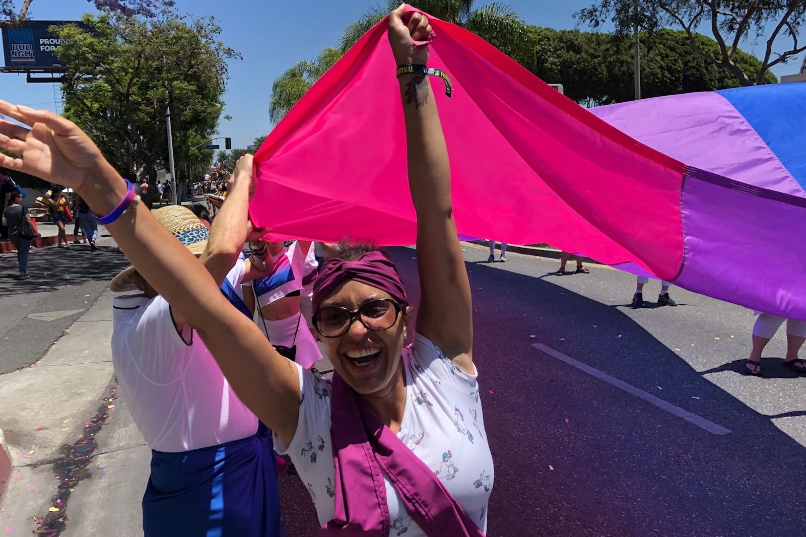 Lorien smiling holding a part of the bi flag during pride.