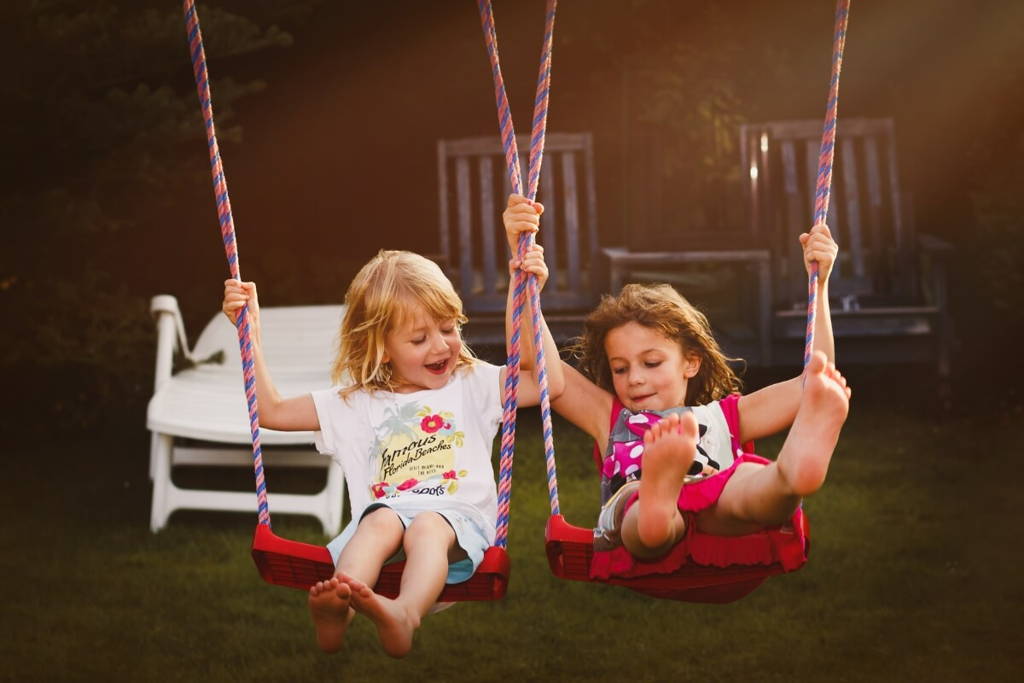 Sisters enjoying playing on a swing.