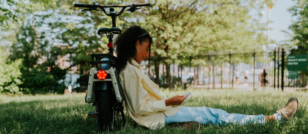 Rider sitting against Specialized Globe Haul electric cargo bike on grass