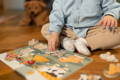 Toddler doing independent quiet play with a wooden animal puzzle on the floor at home.