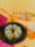 A visually appealing arrangement of green sweets on a black plate, with scattered nuts and a vibrant background.