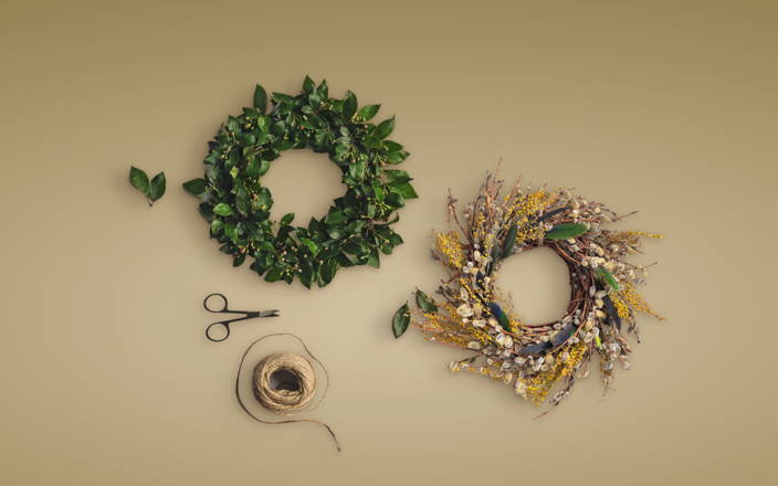 Scissors and twine next to a green wreath and a gold and tan decorative wreath for Confetti's Virtual Holiday Wreath Workshop