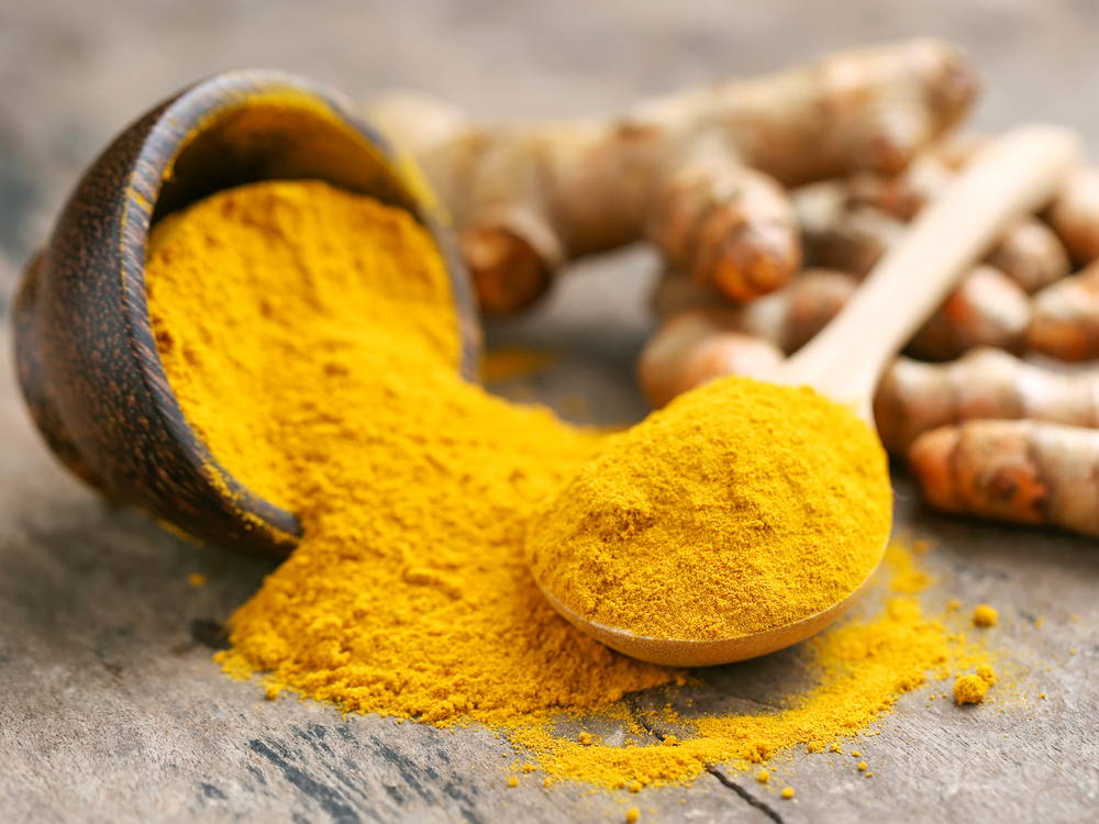 Turmeric root and powder on wooden table