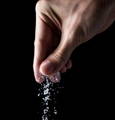 A hand sprinkles a pinch of MSG