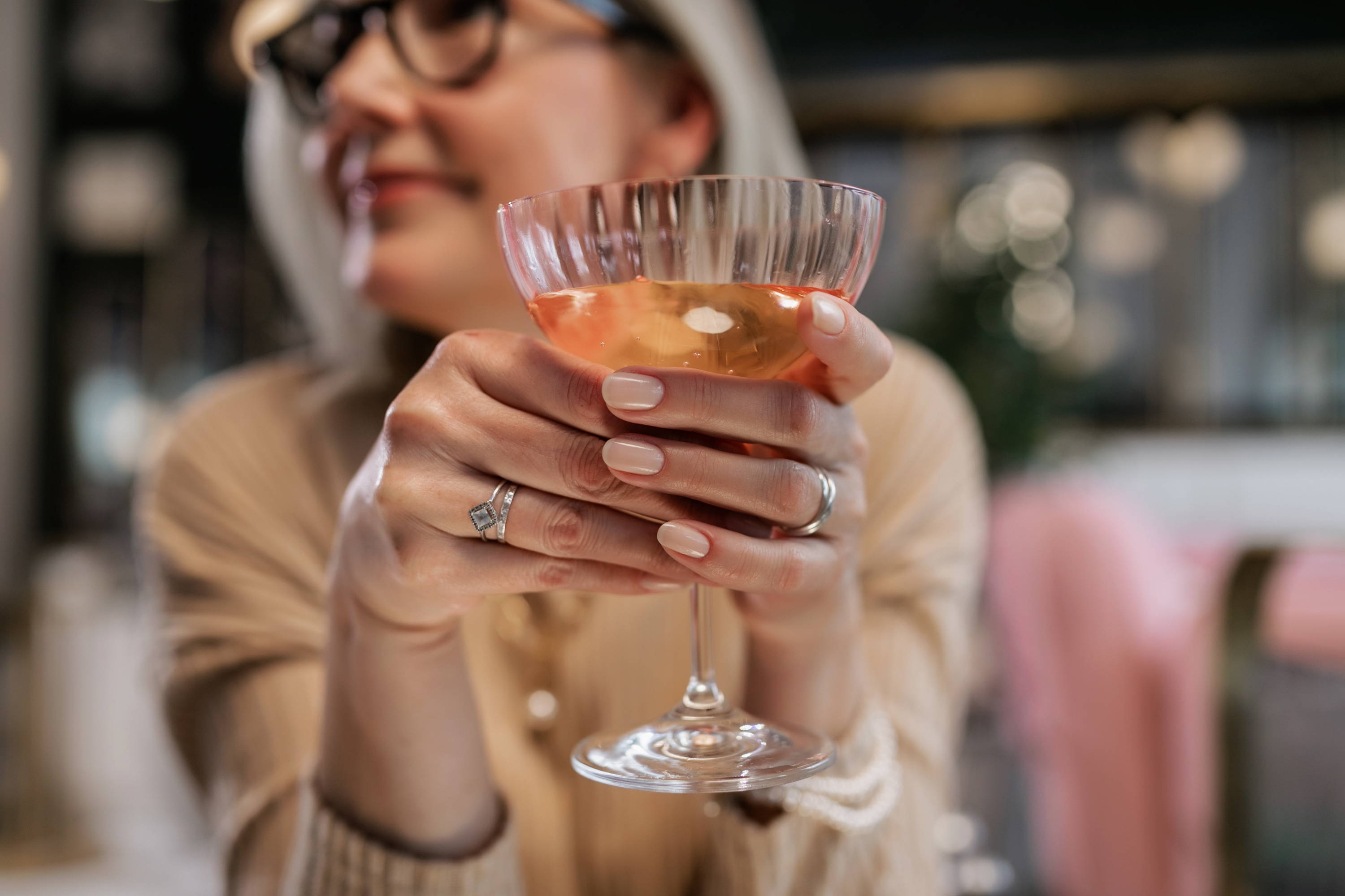 Lady holding a glass of orange wine to uncover the flavours of peach, apricot and pineapple, as well as orange blossom, beeswax and honey. 