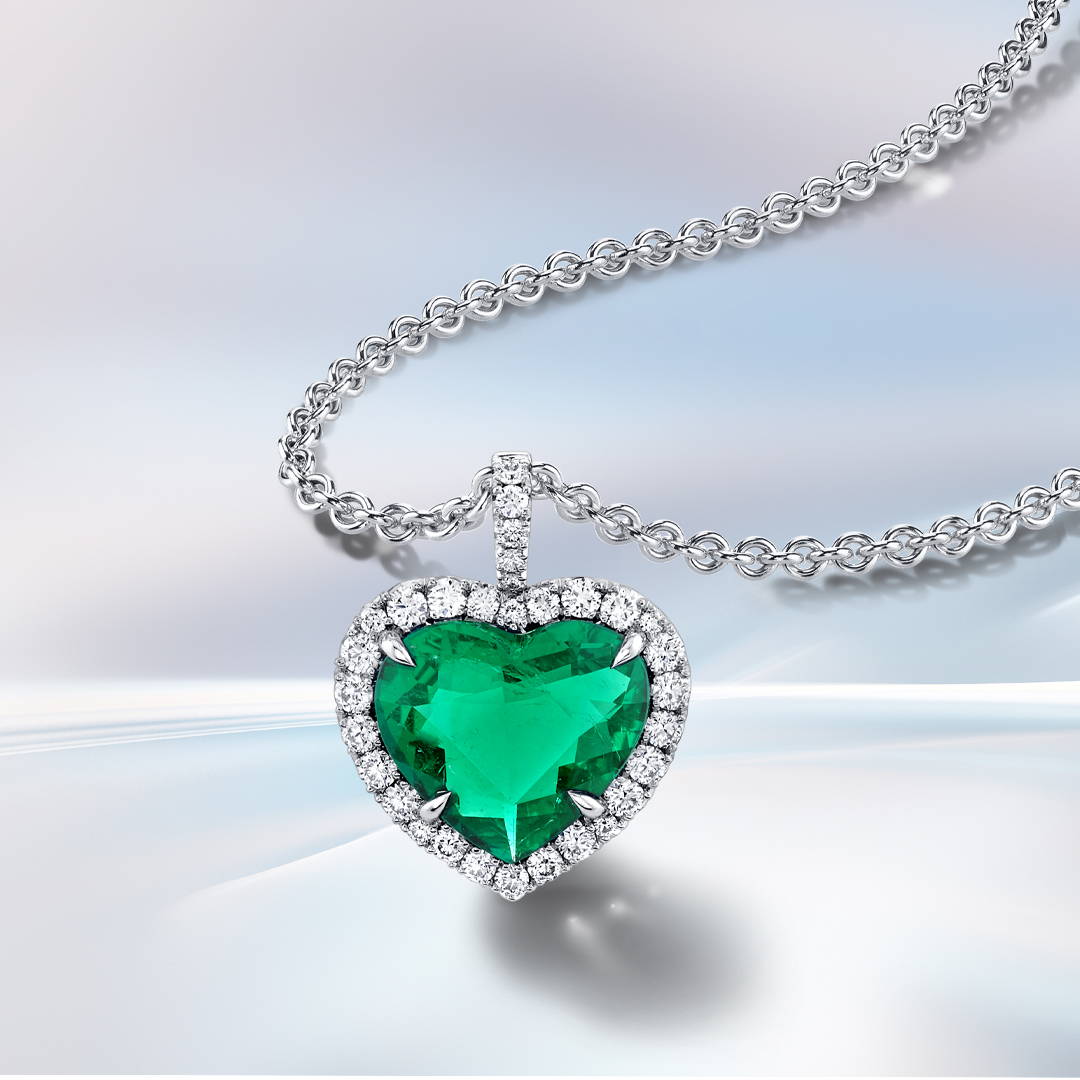 Emerald heart shaped pendant with diamond accents in white gold.