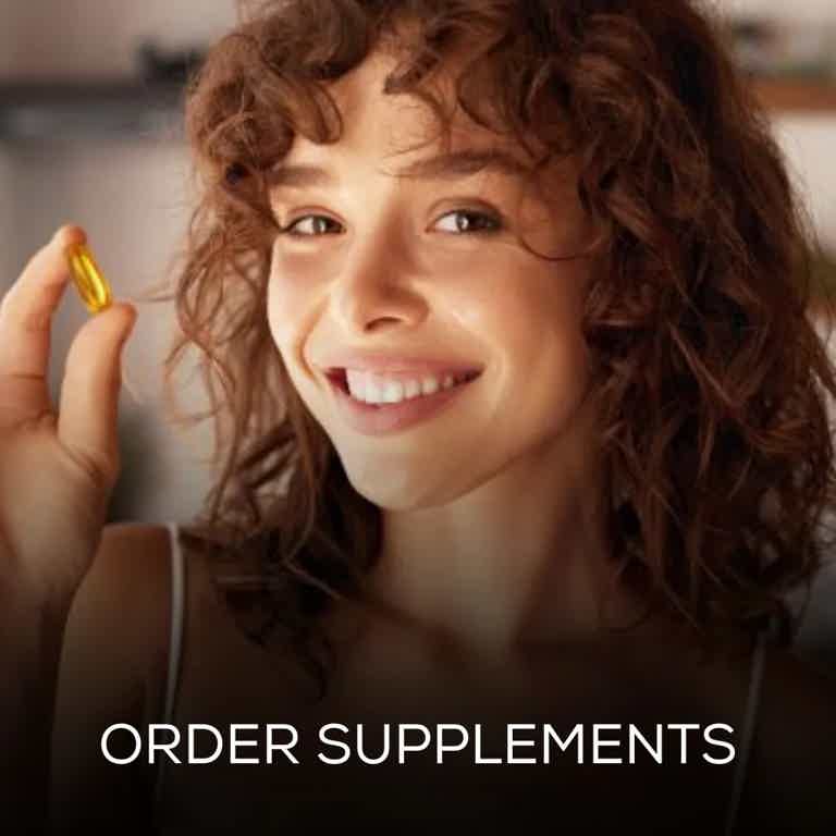 Smiling woman holding a yellow supplement capsule, promoting health and wellness in a bright indoor setting.