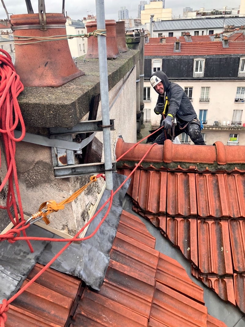 Couvreur-cordiste sur une toiture en tuile à Paris