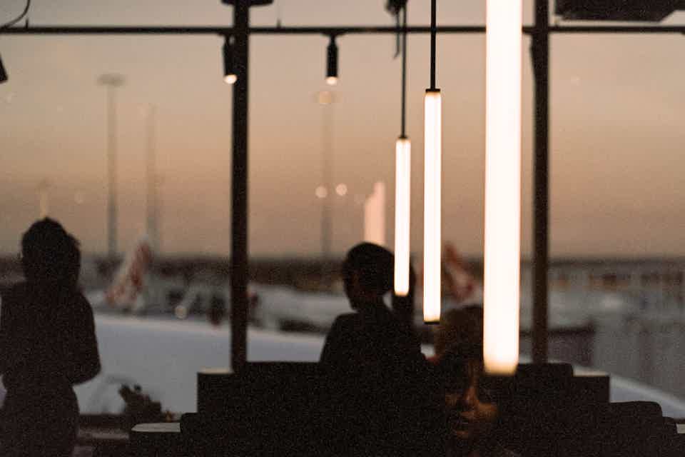 Silhouette of cafe with airport scenery outside large window during sunset