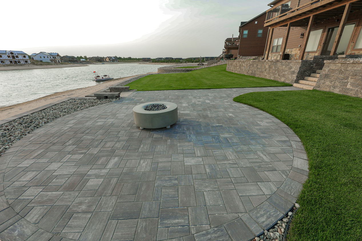 large circular patio on a water front property with a fire pit on top of it.