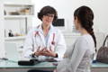 a pregnant woman consulting with a female doctor about the safety of taking green supplements while pregnant