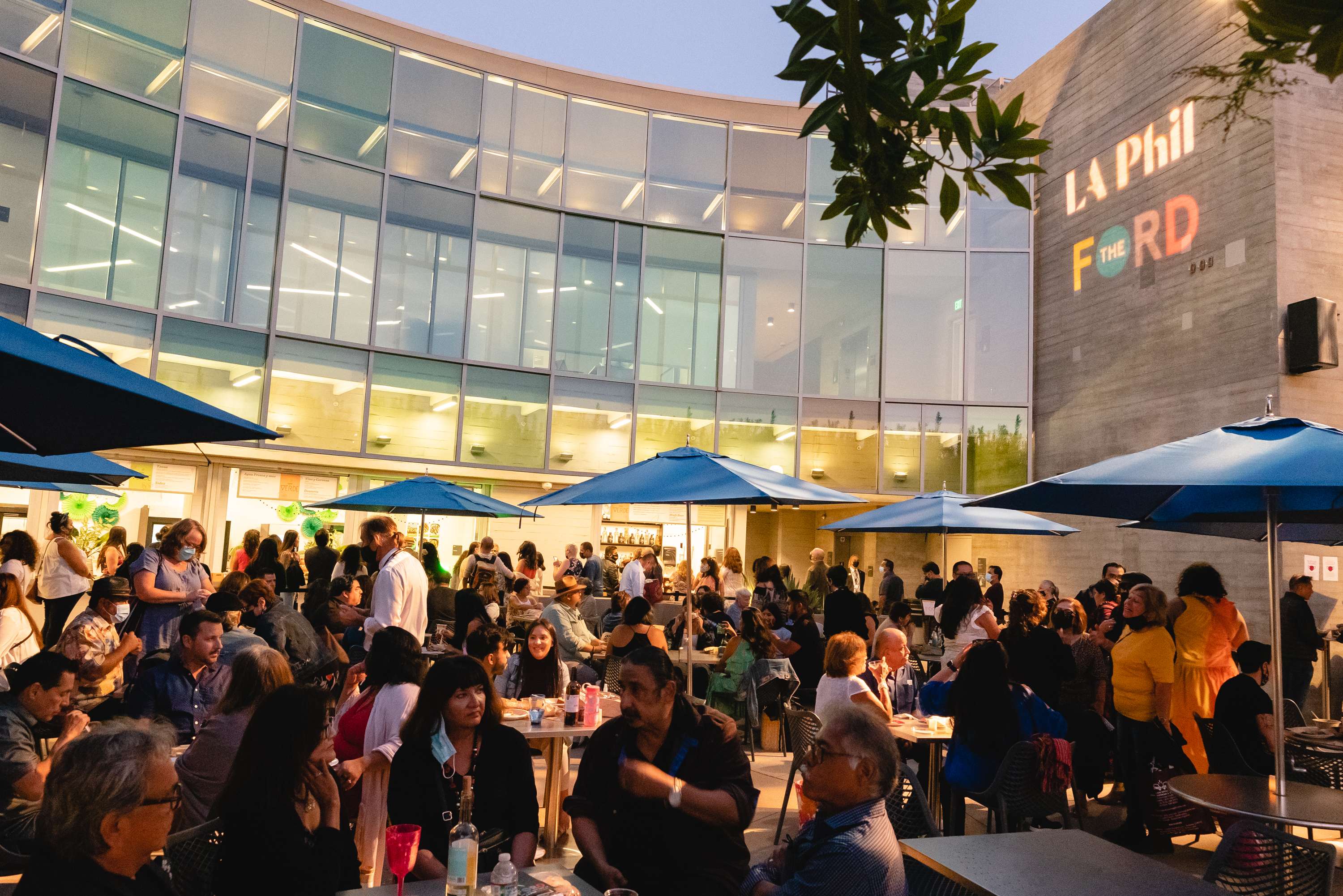 The Ford Terrace at night time is packed with hungry concertgoers. The LA Phil and Ford logos are projected onto the building in the background.