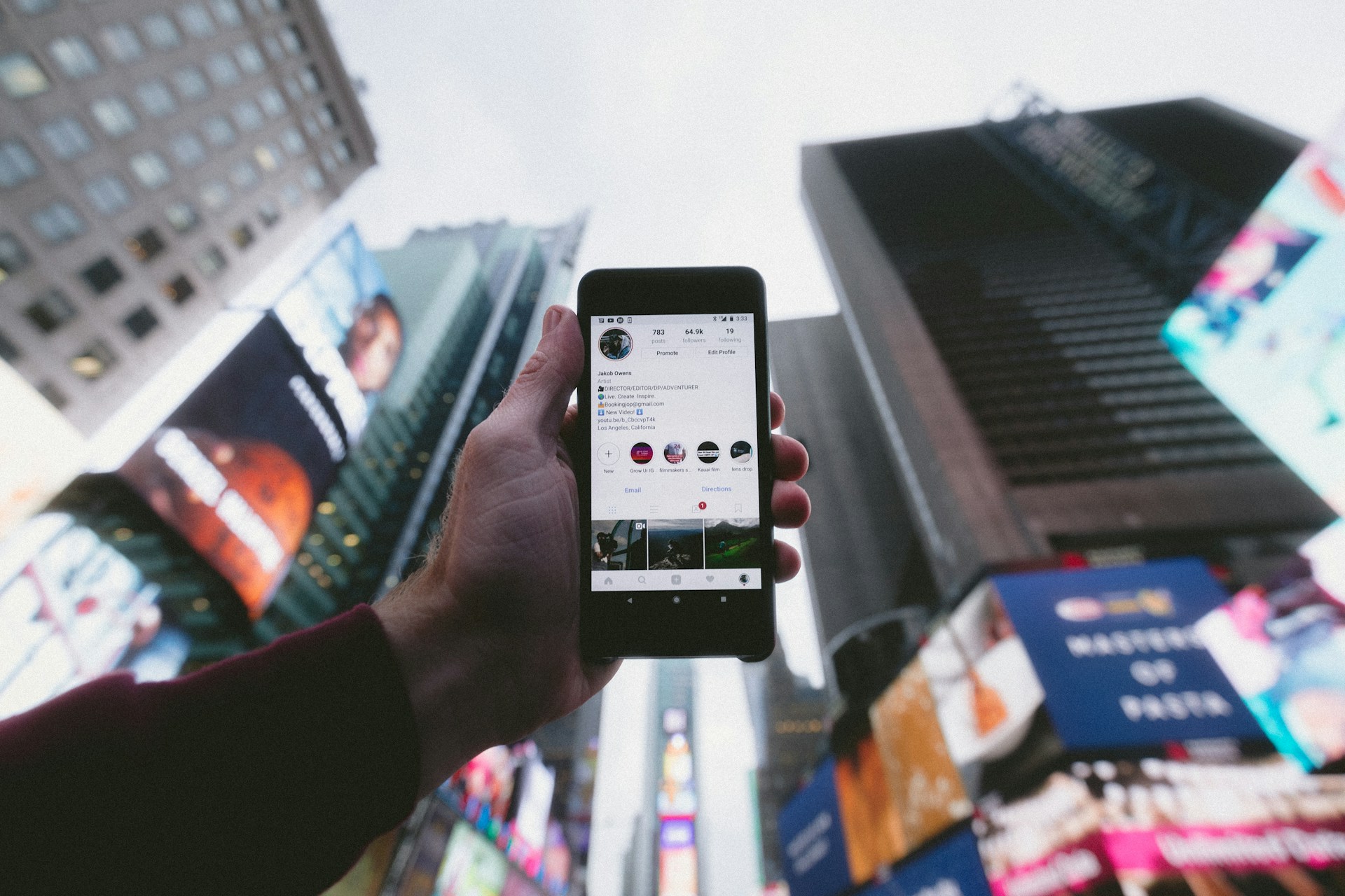 Someone holding a smartphone up to the sky in a city showing Instagram on the screen