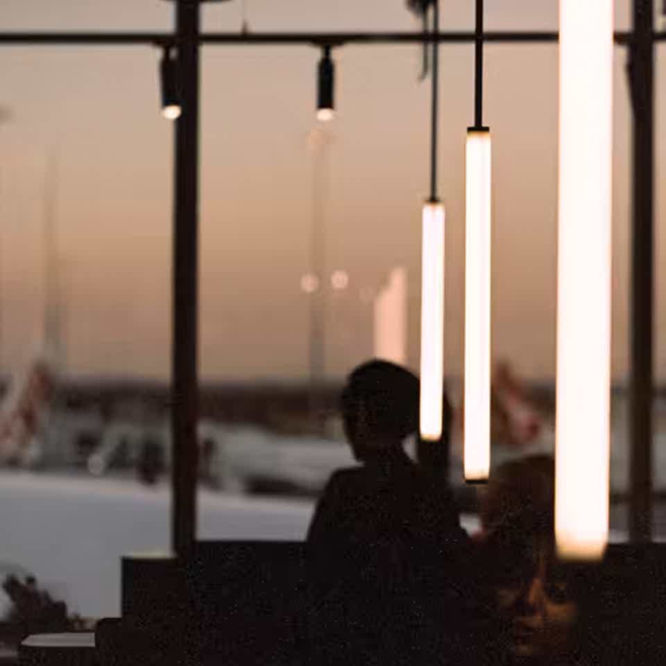 Silhouette of cafe with airport scenery outside large window during sunset