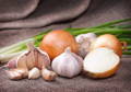 Onions, garlic, and chives displayed in a group.