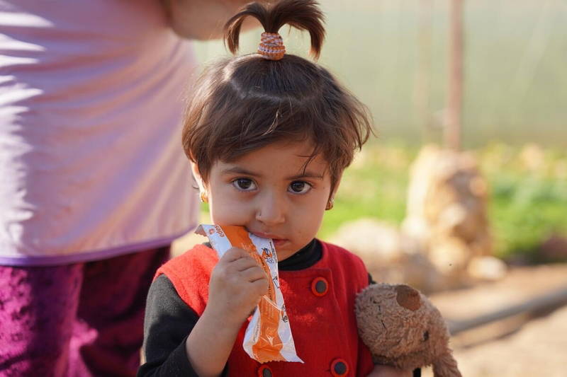 Two-year-old Syrian girl eating a nutritional peanut paste from WFP