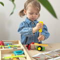 Girl constructing an airplane model using a wrench and pieces from the Montessori Wooden Toolbox set.