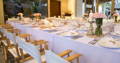 wedding reception with white tablecloth, napkins and chairs, completely set up with plates, curtailery and flowers