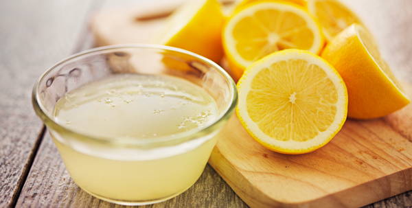 Citron coupé avec un bol de jus de citron concentré.
