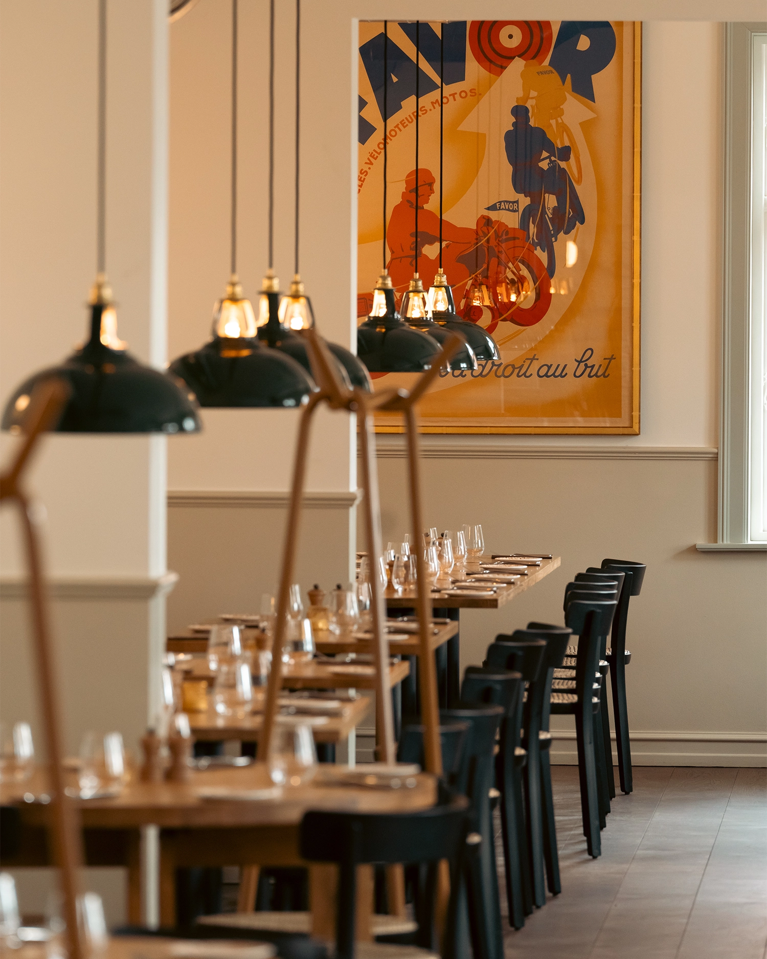 Looking down a Scandinavian restaurant at two rows of tables with Large Green Coolicon lampshades hanging above each one. 