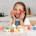 Little girl holding two Montessori wooden rocks and smiling. 