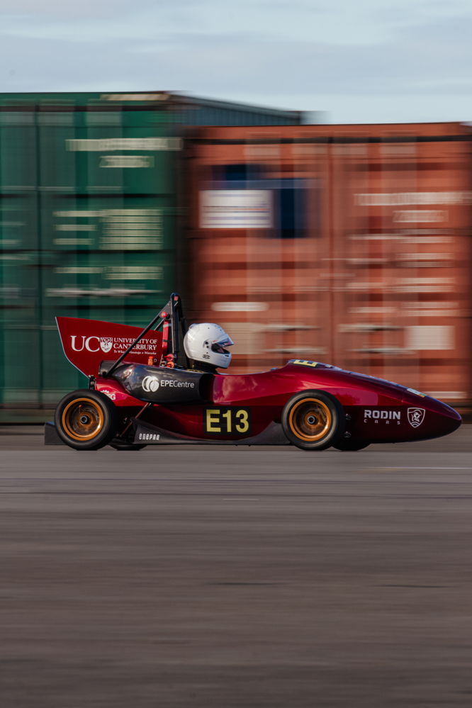 Panning shot of car driving in front of containers