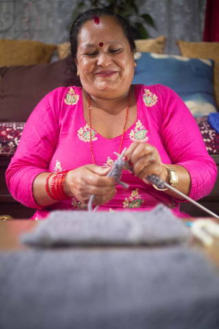 Woman smiling while knitting.