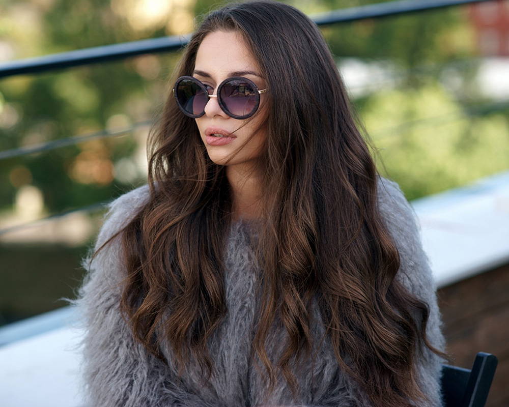 A young woman wearing very long brunette tape in hair extensions sitting in a chair at a cafe