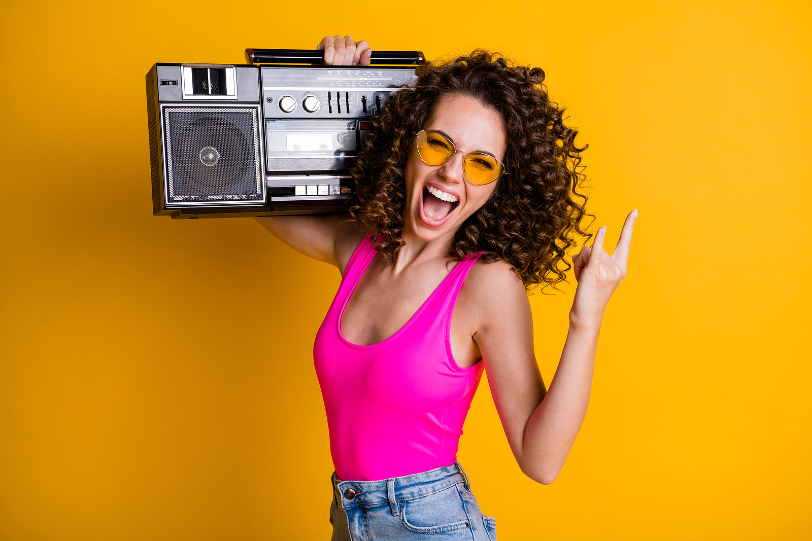 Photo of cool youngster lady with wavy hairdo listening to music holding a retro boom box.