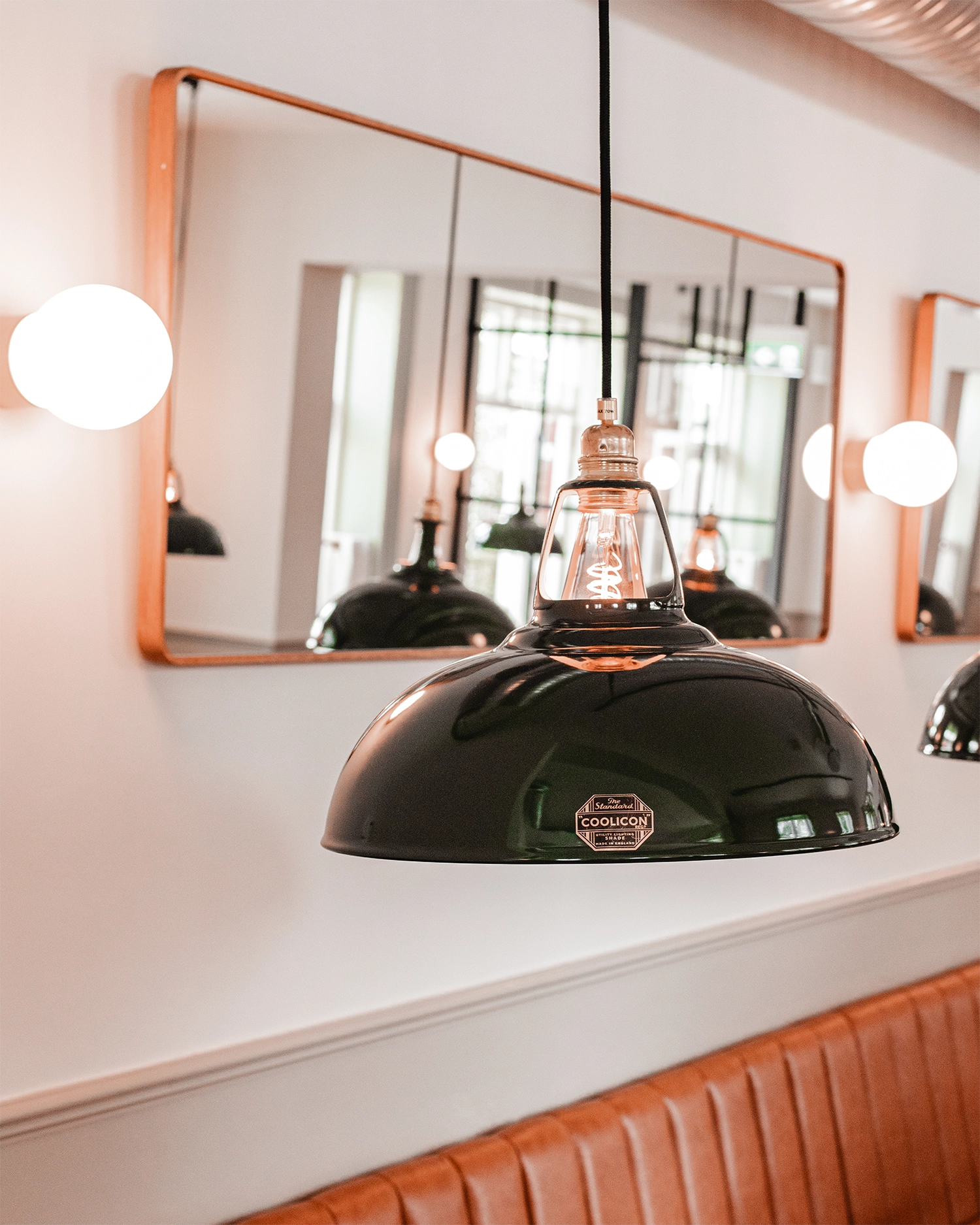 A close up of a large green Coolicon Lampshades in front of a rectangular mirror.
