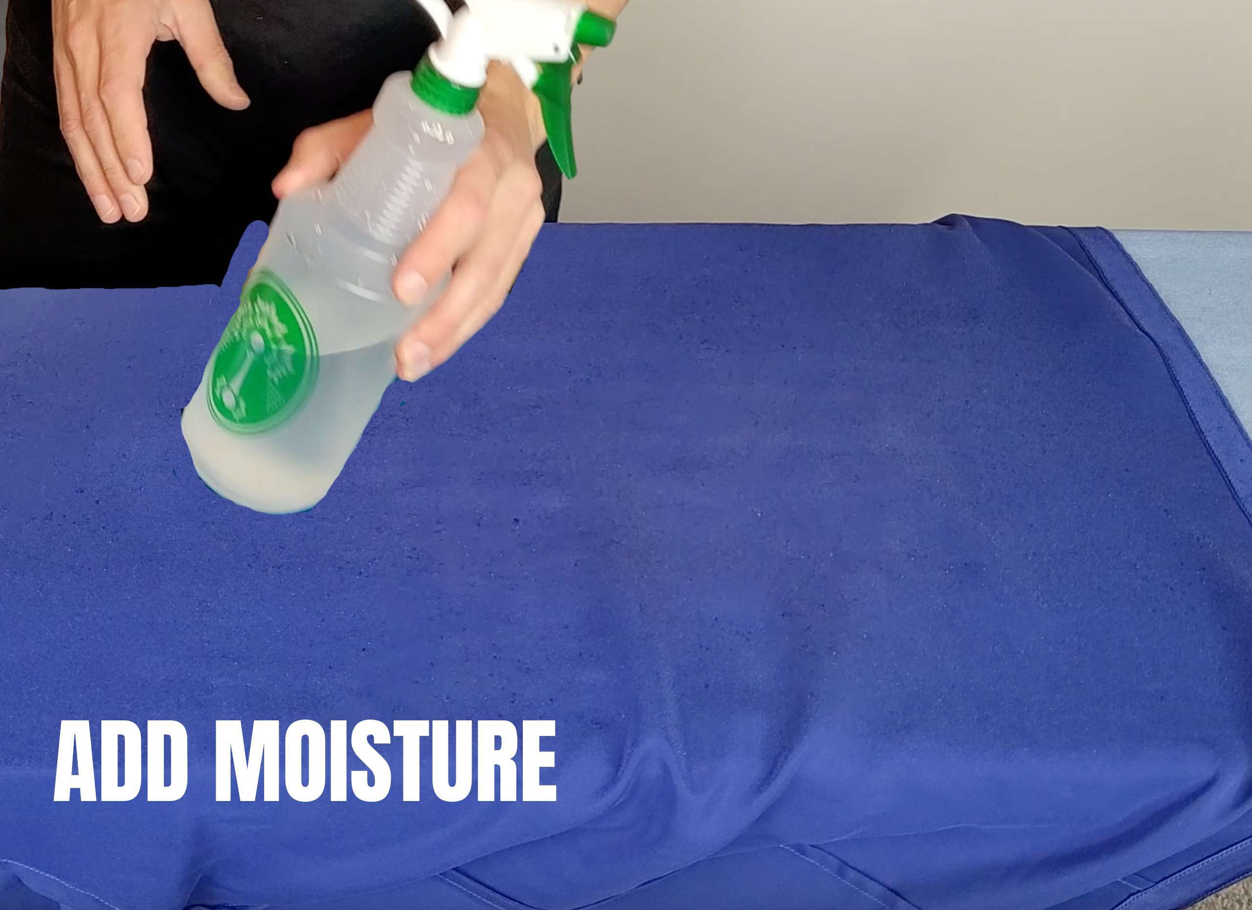 photo of a man using a spray bottle filled with water to add moisture to satin pajamas