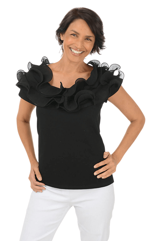 A woman wears a black blouse with ruffled accents against a beige background