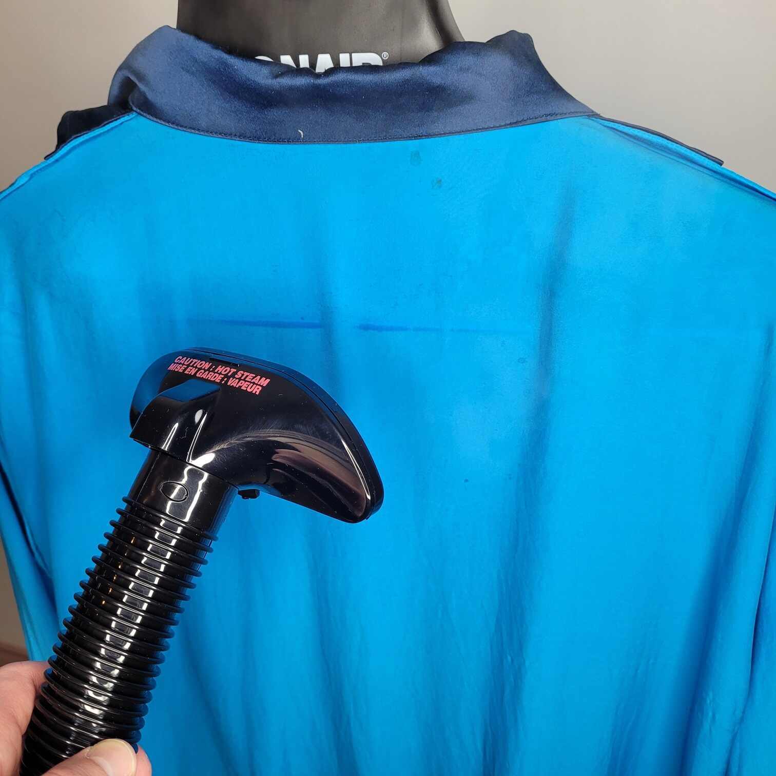 photo of a person using a steamer to get wrinkles out of a satin garment
