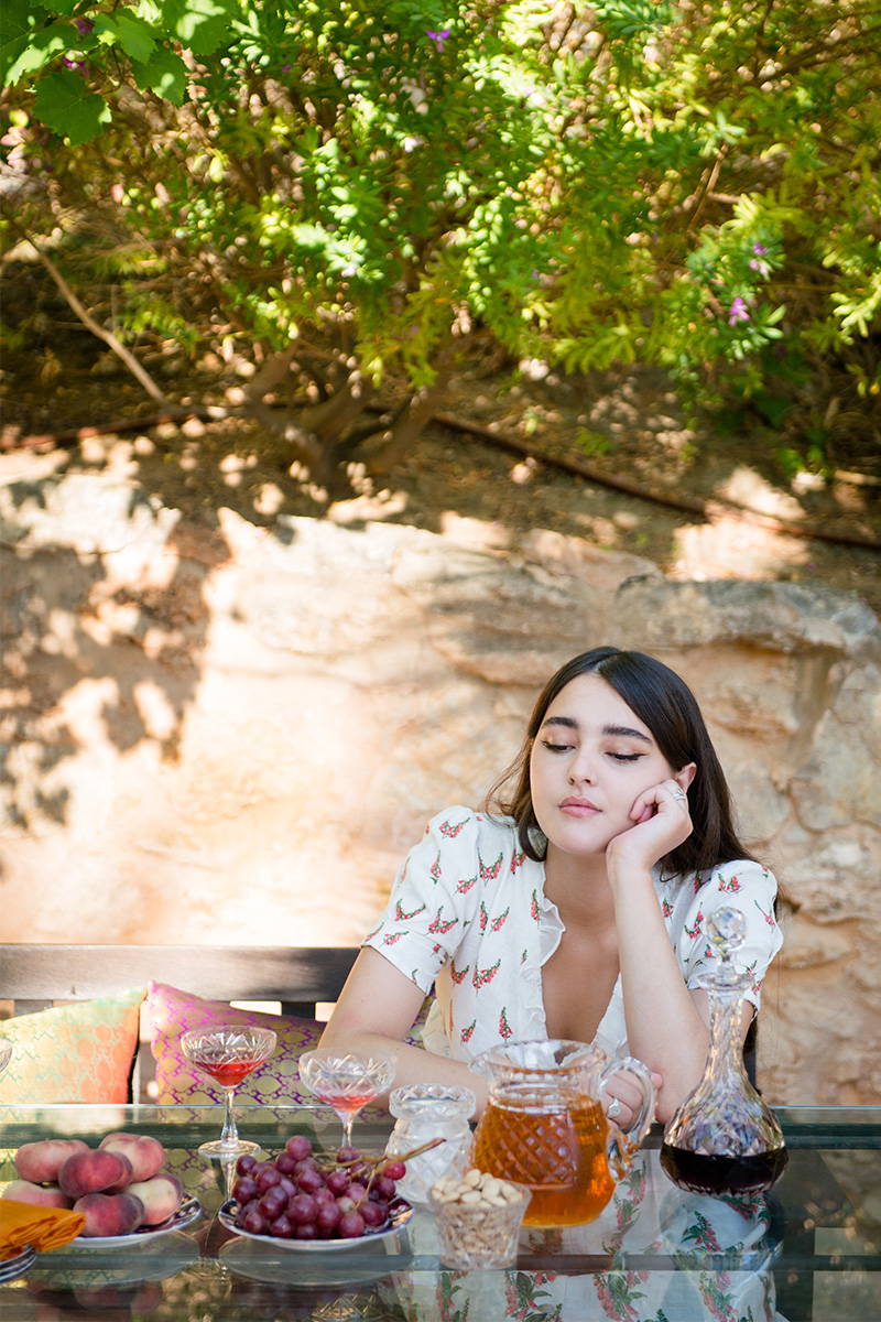 Madeline Mills daydreams at the lunch table whilst wearing YOLKE Foxglove Valentina Dress