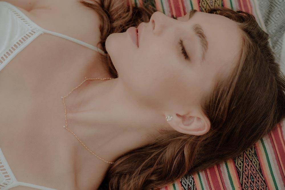 Woman wearing Sceona gold necklace and gold earrings