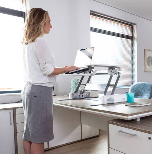 A woman works at her Ergotherapy Standing Desk Converter