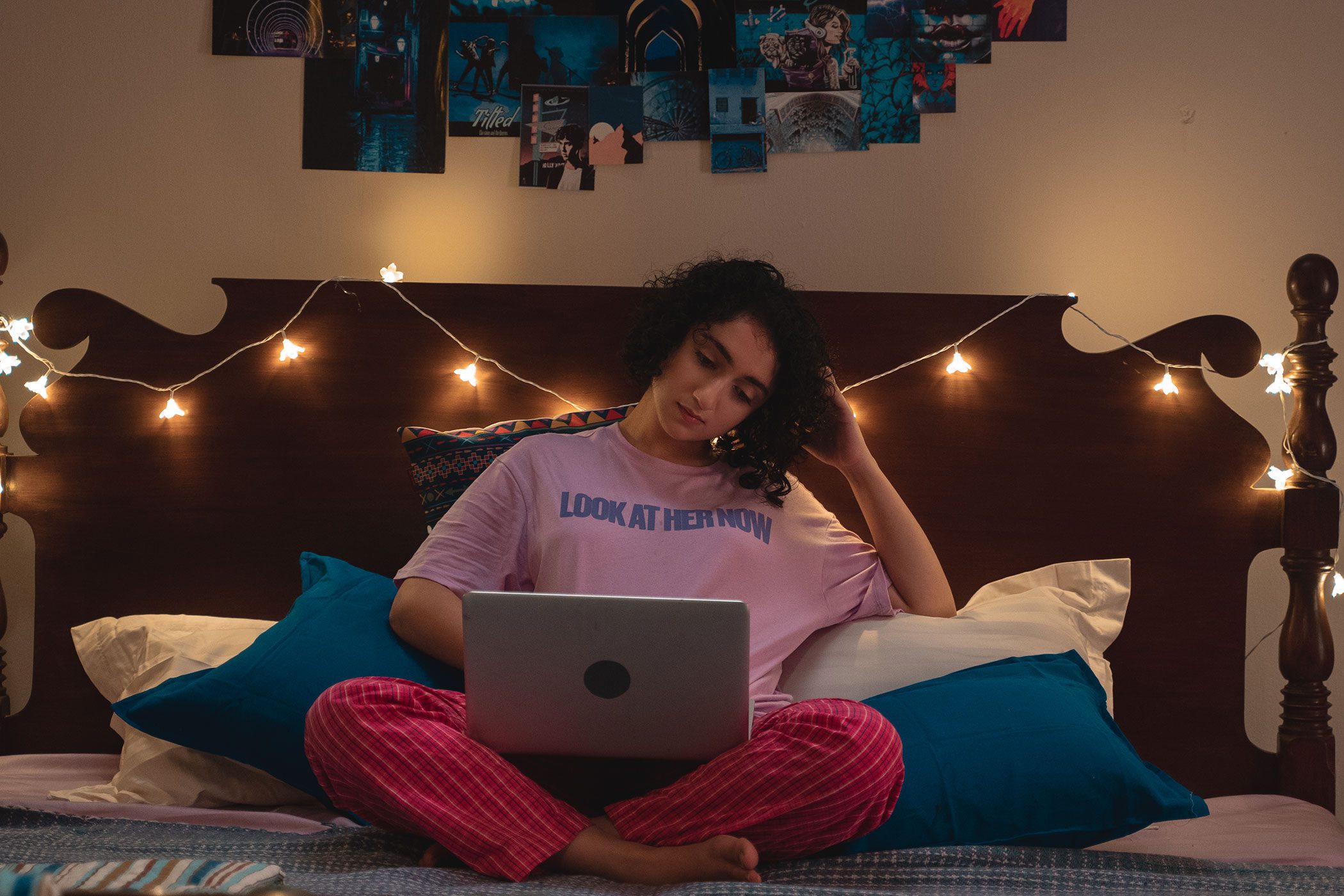 Muskaan sitting cross legged on her bed looking at her laptop and with her head against her hand