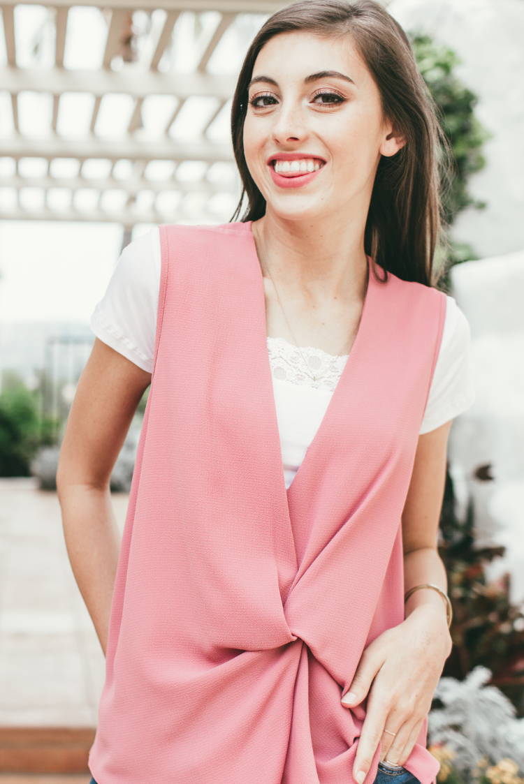 A woman wearing jeans and a pink vest.
