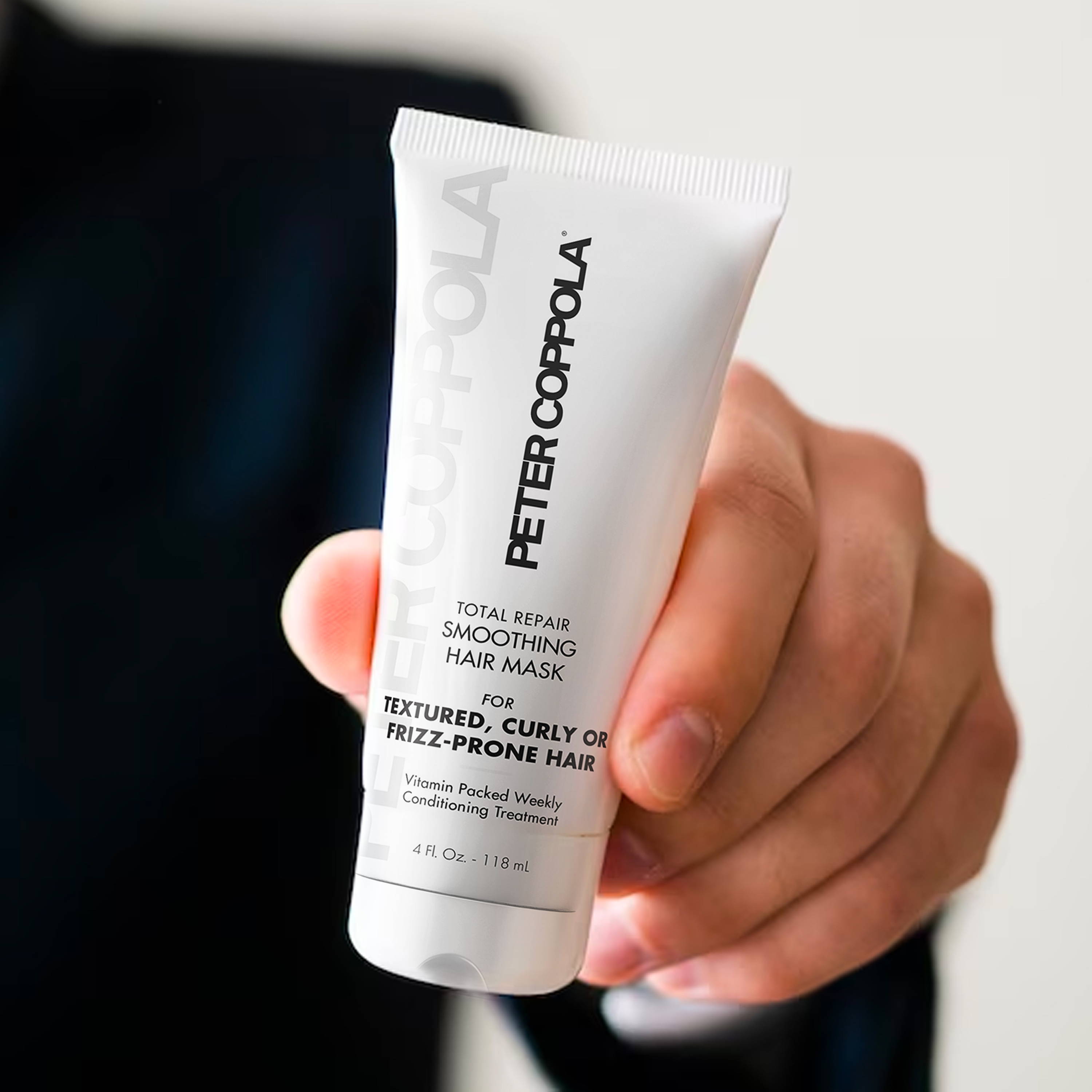 a hand holding a 4 ounce tube of total repair smoothing hair mask