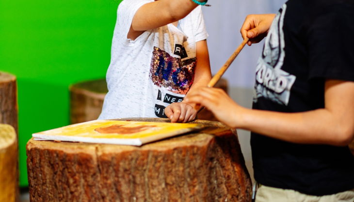 steinzeitkunst kinder mit holzbohrer in der steinzeitwerkstatt