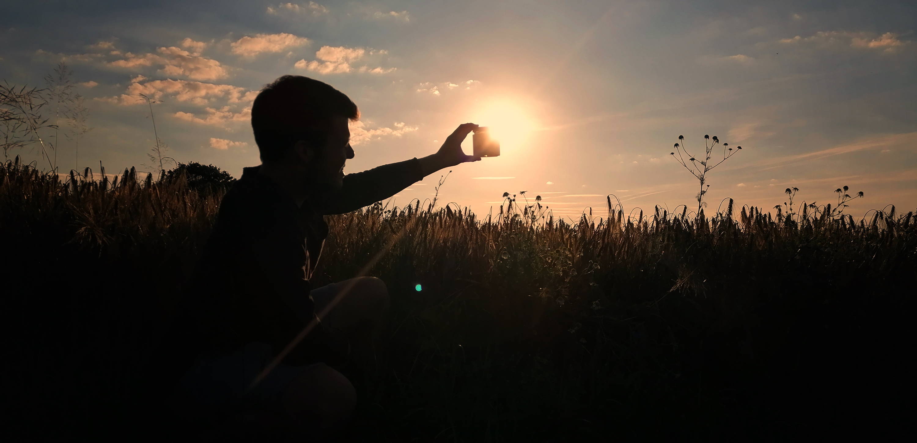 Mann mit Glas in der Hand im Feld im Sonnenuntergang