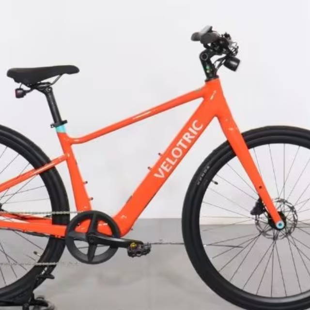 an orange velotric electric city bike