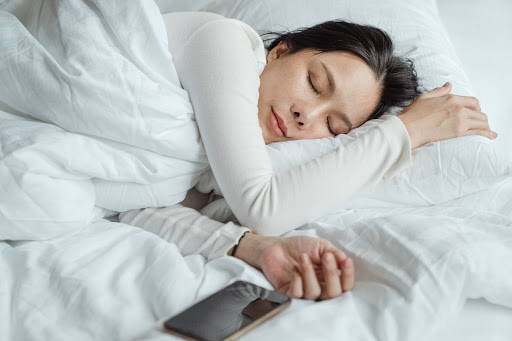 A woman sleeping peacefully in bed, under a blanket - Photo by Ketut Subiyanto from Pexels