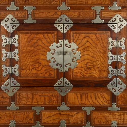 Detail of an antique Korean cabinet with brass detailing on burr red elm