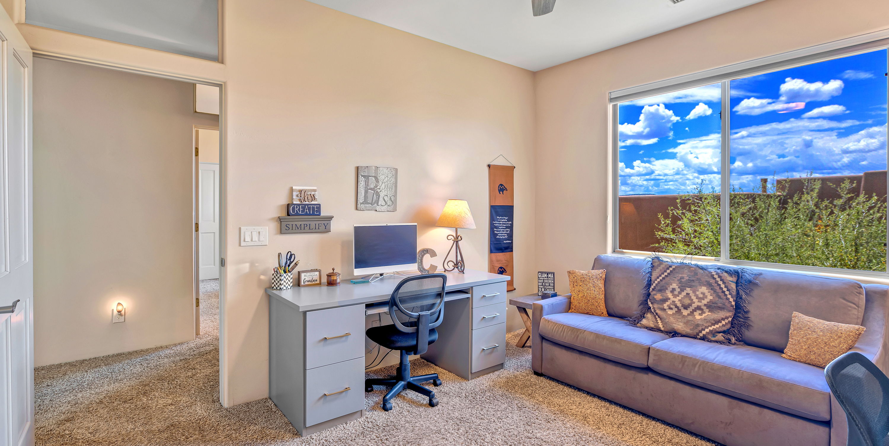 carpeted home office with a ceiling fan, natural light, and TV