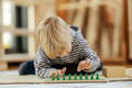Little boy playing with green Montessori pegs.